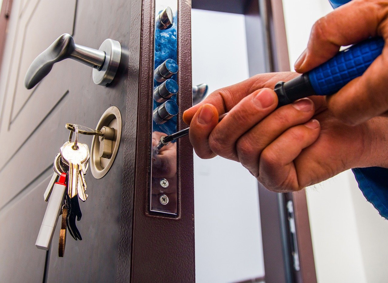 a hand holding a screwdriver and opening a lock, Trustworthy Locksmith